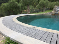 Piscina con bordo curvo e griglia Sfioro in pietra naturale